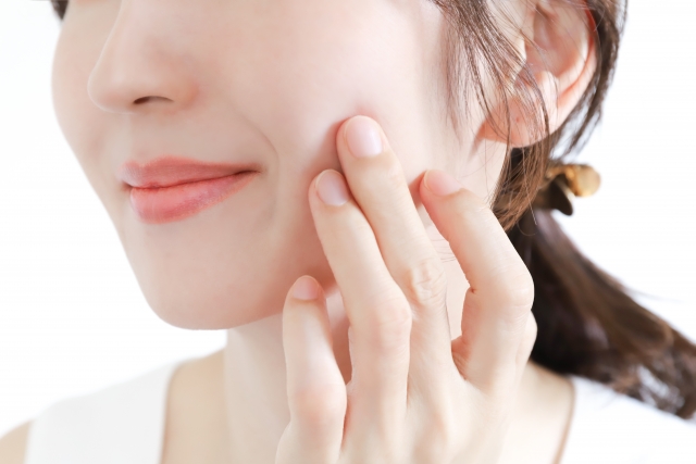 頬を触る女性の画像