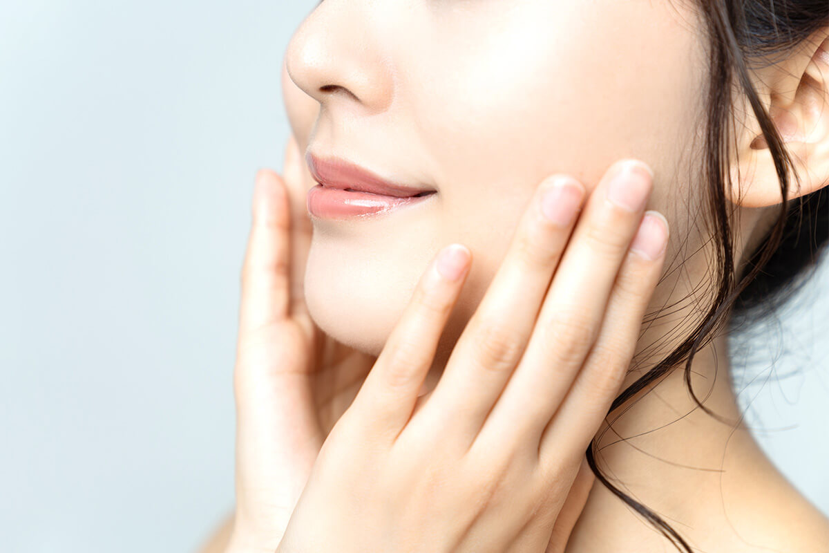 顔に手を添えてほほ笑む女性