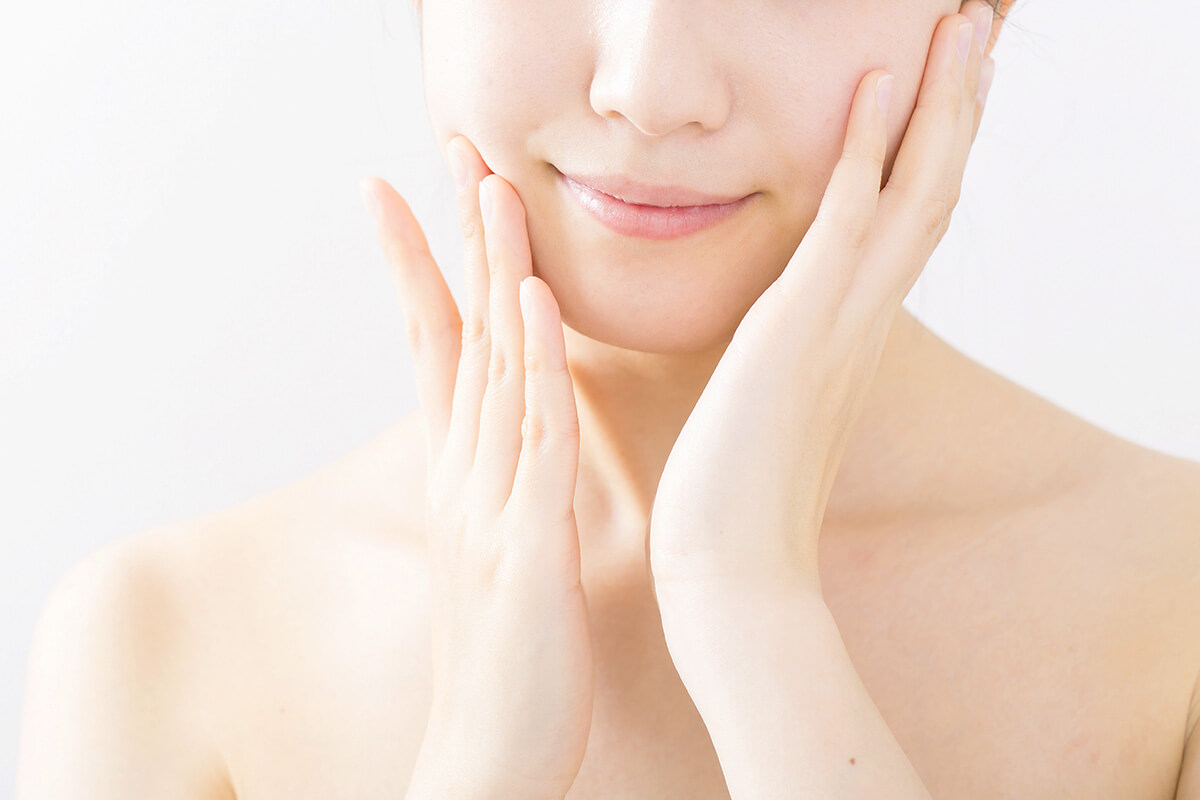 ほほに両手を添えてほほ笑む女性