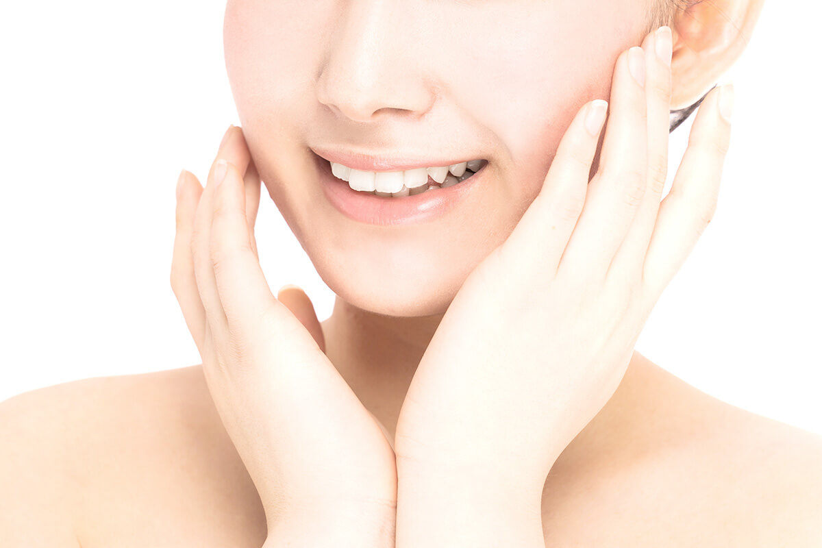 顔に両手を添えてほほ笑む女性