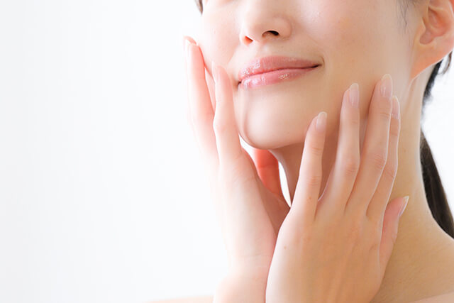 斜め上を向いて両手を顔に添える女性