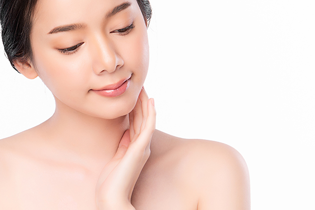 首をかしげ顔に手を添える女性